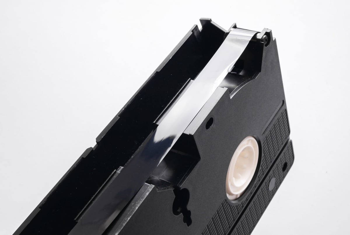 Film tape of VHS video cassette close up on white background